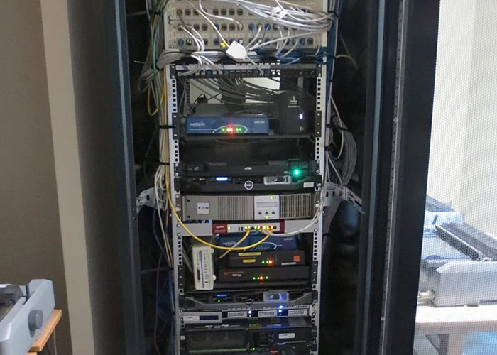 Un technicien installe des câbles à fibre optique dans un centre de données, manipulant des connexions de câblage avec précision.